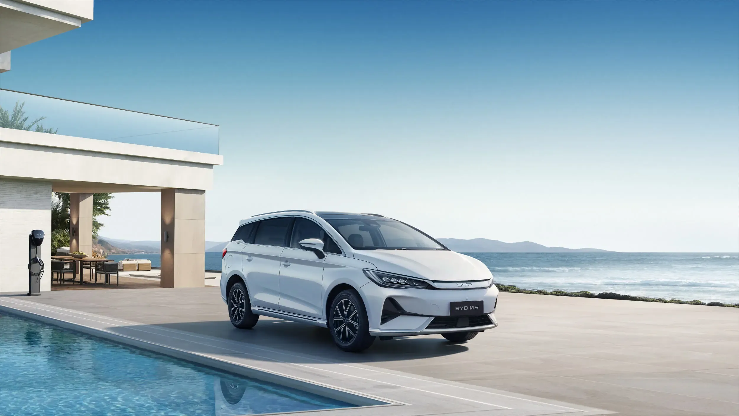BYD M6 car parked in front of a modern villa